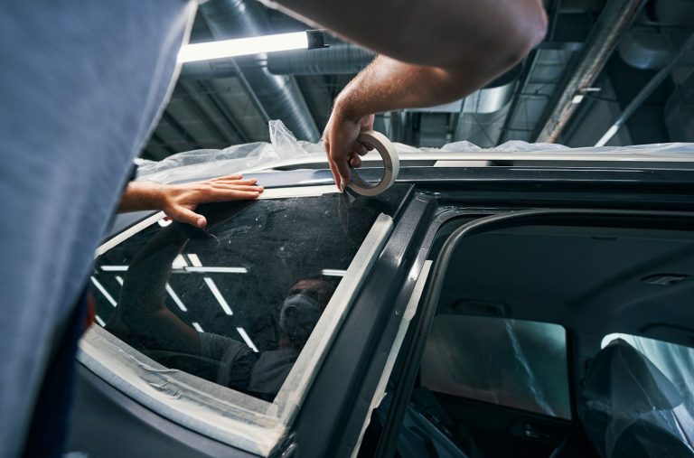 Eine Person bringt eine Folie an einem Autofenster an.